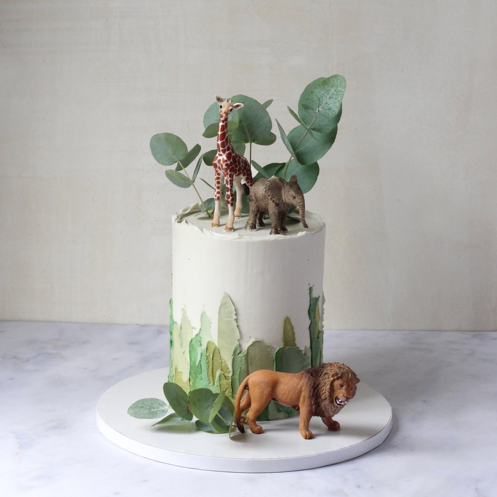 The Safari Tour Cake - perfect for the wild kids that dreams the safari life! Decorated with brushstrokes, Eucalyptus leaves and Schleich figurines.