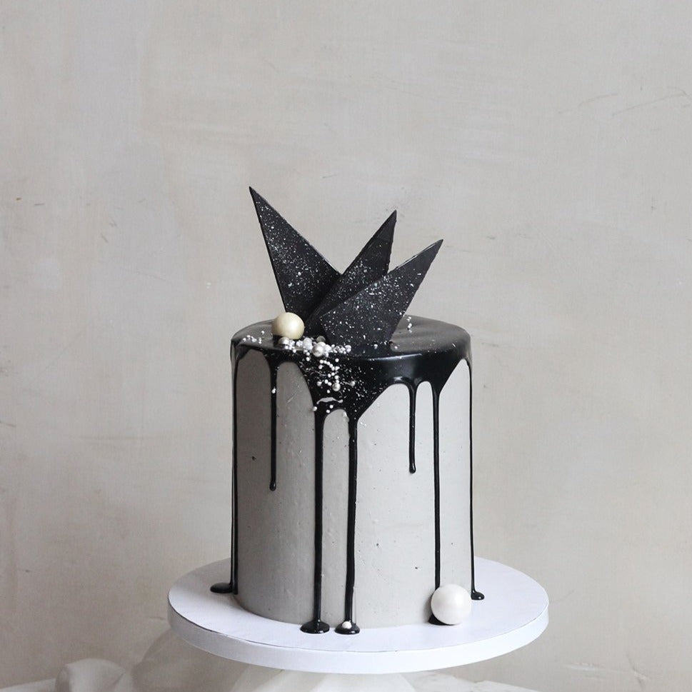 The Concrete Cake - dipped in  black drip icing, with geometric chocolate forms.