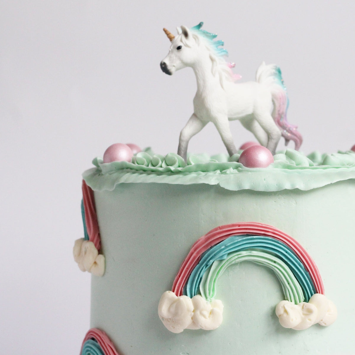 Our Rainbow Cake with peach &amp; mint ombre icing, 3D rainbows, creamy ruffles &amp; unicorn topper!