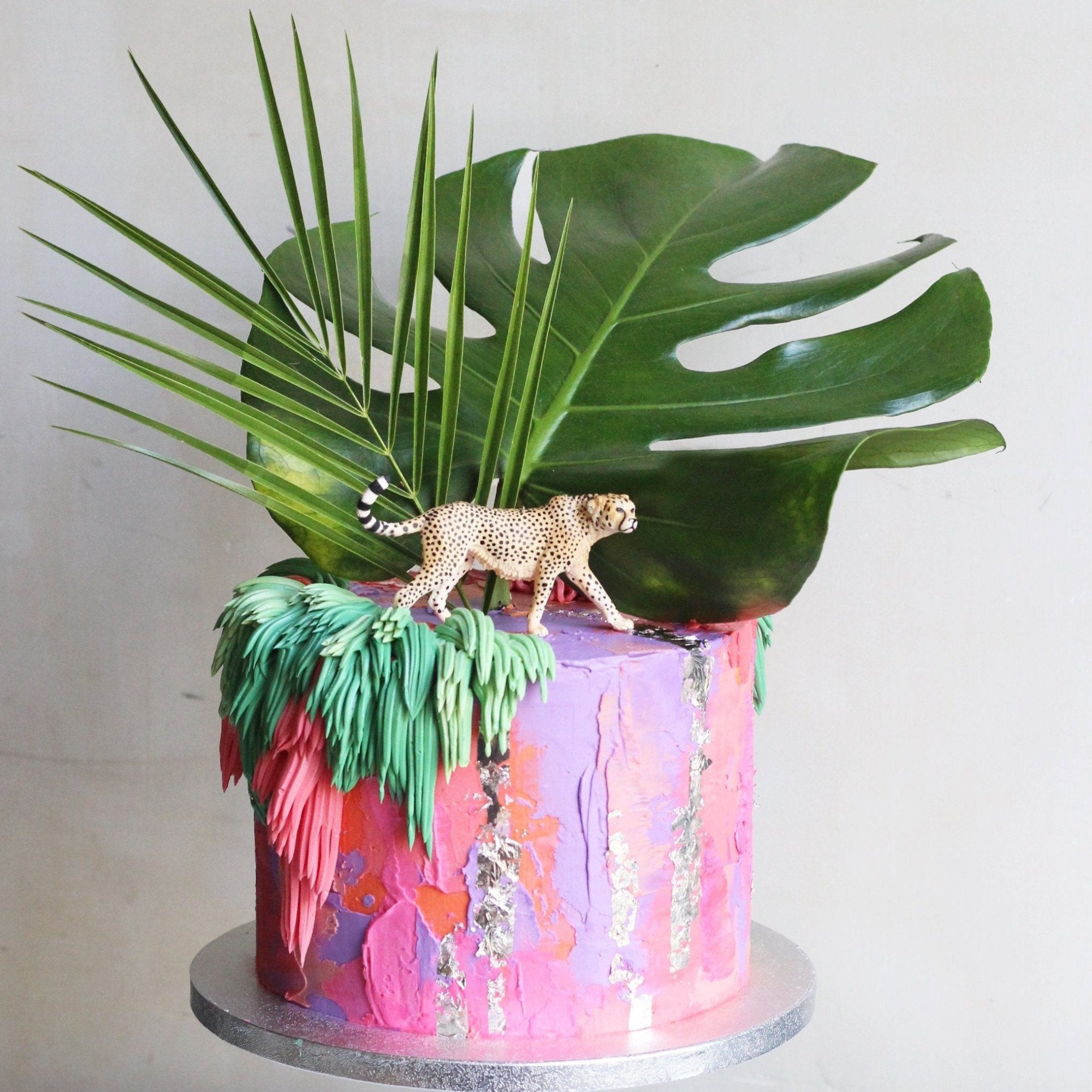 Colorful bold cake and shaggy details, decorated with green leaves and a Schleich cheetah topper.