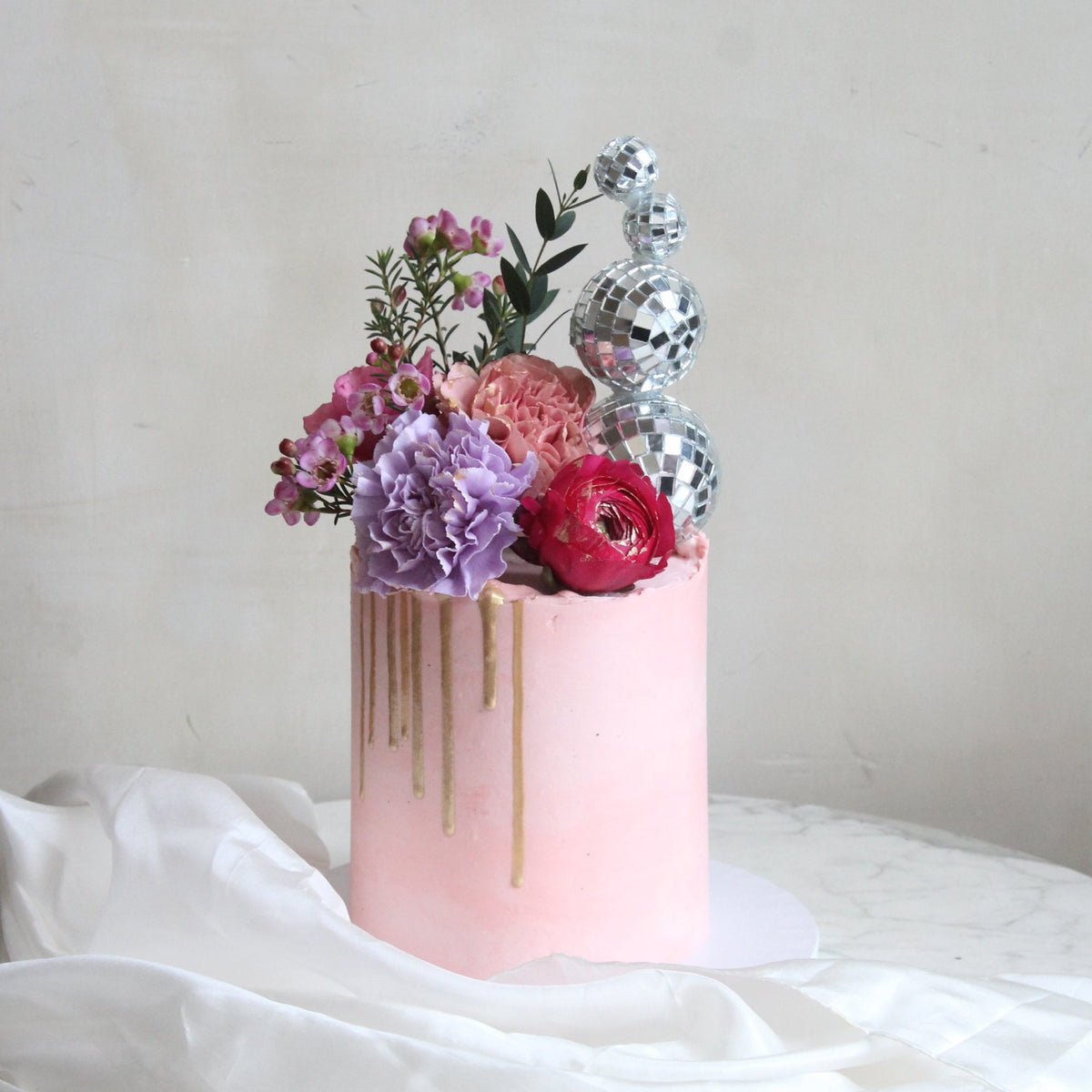 Meet the Golden Hour Cake - a dazzling showpiece for every disco queen! Covered in pink icing, topped with bold florals, shimmering gold drip, and sparkling disco balls. Perfect for birthdays, parties, and glamorous celebrations.