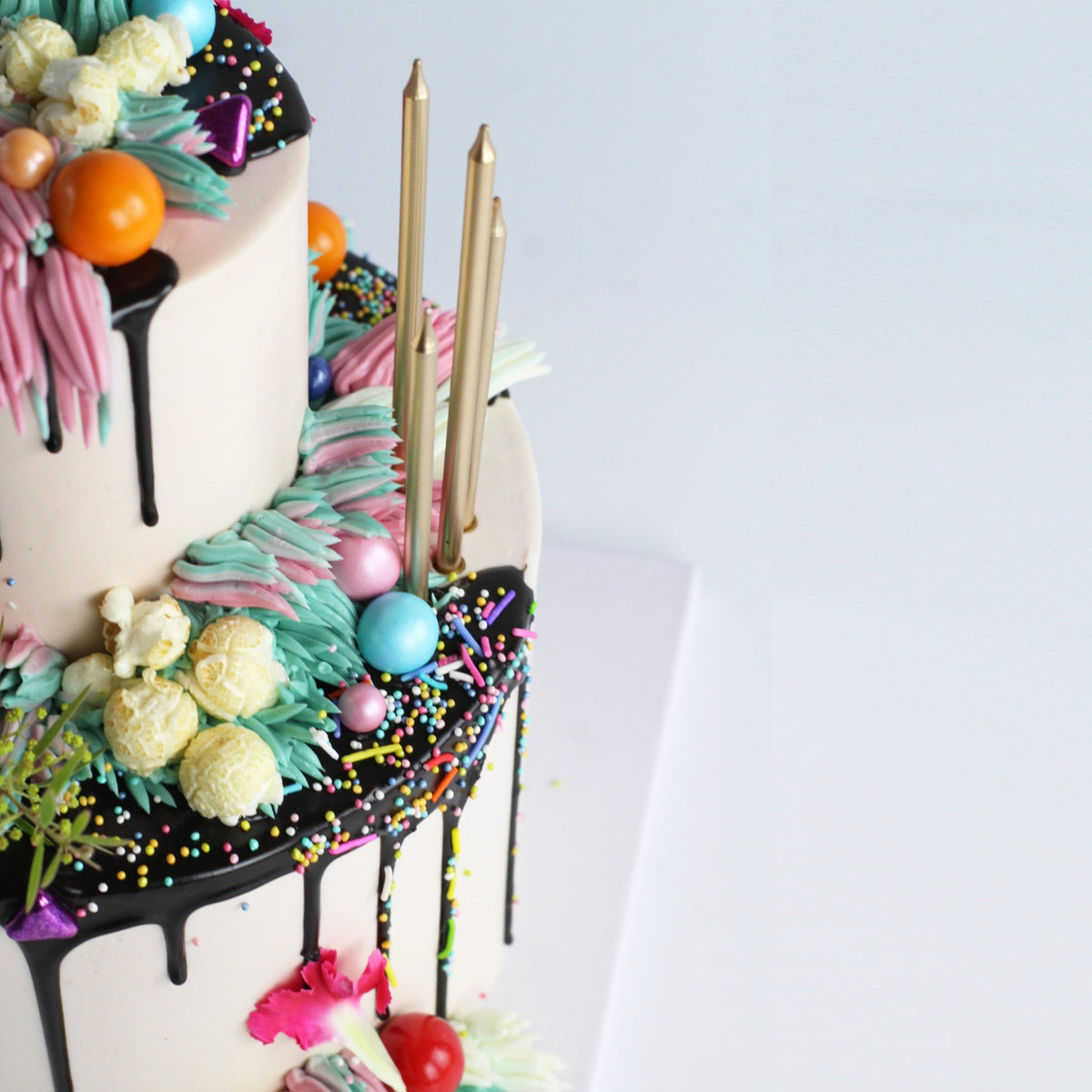 Two-tier Over The Top Cake with flowers, shaggy buttercream icing, sprinkles, candy pearls and popcorn!